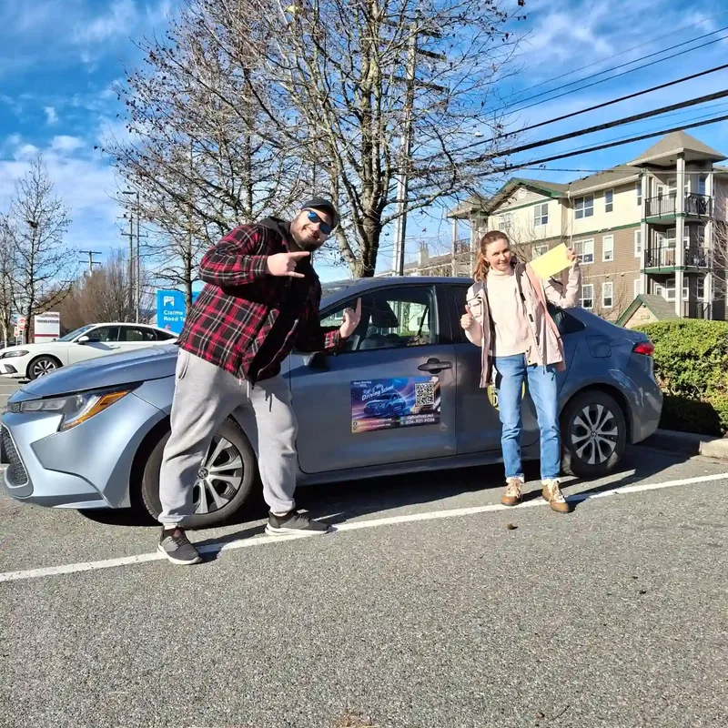 Right of Way student celebrating with their road-test result beside the training car in Chilliwack
